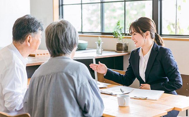 夫婦と打ち合わせをしている営業の女性