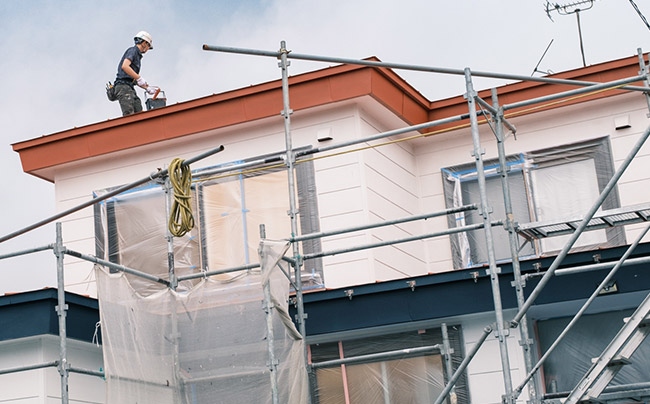 屋根塗装をしている従業員